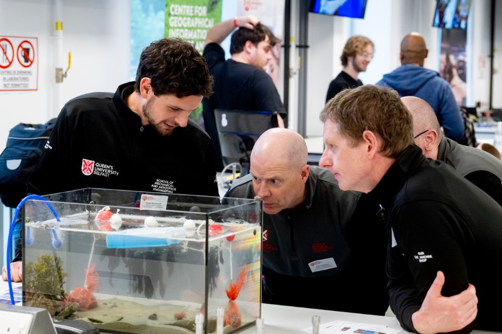 technicians demonstrating and chatting over a marine lab display table at the Technician Showcase 2024